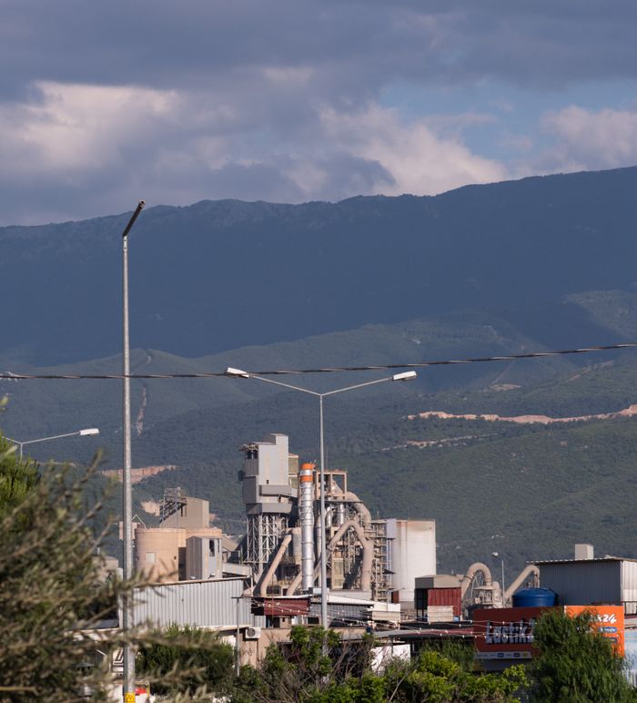 Industrial factory scene with mountain backdrop near İzmir, Türkiye, showcasing a blend of nature and industry.